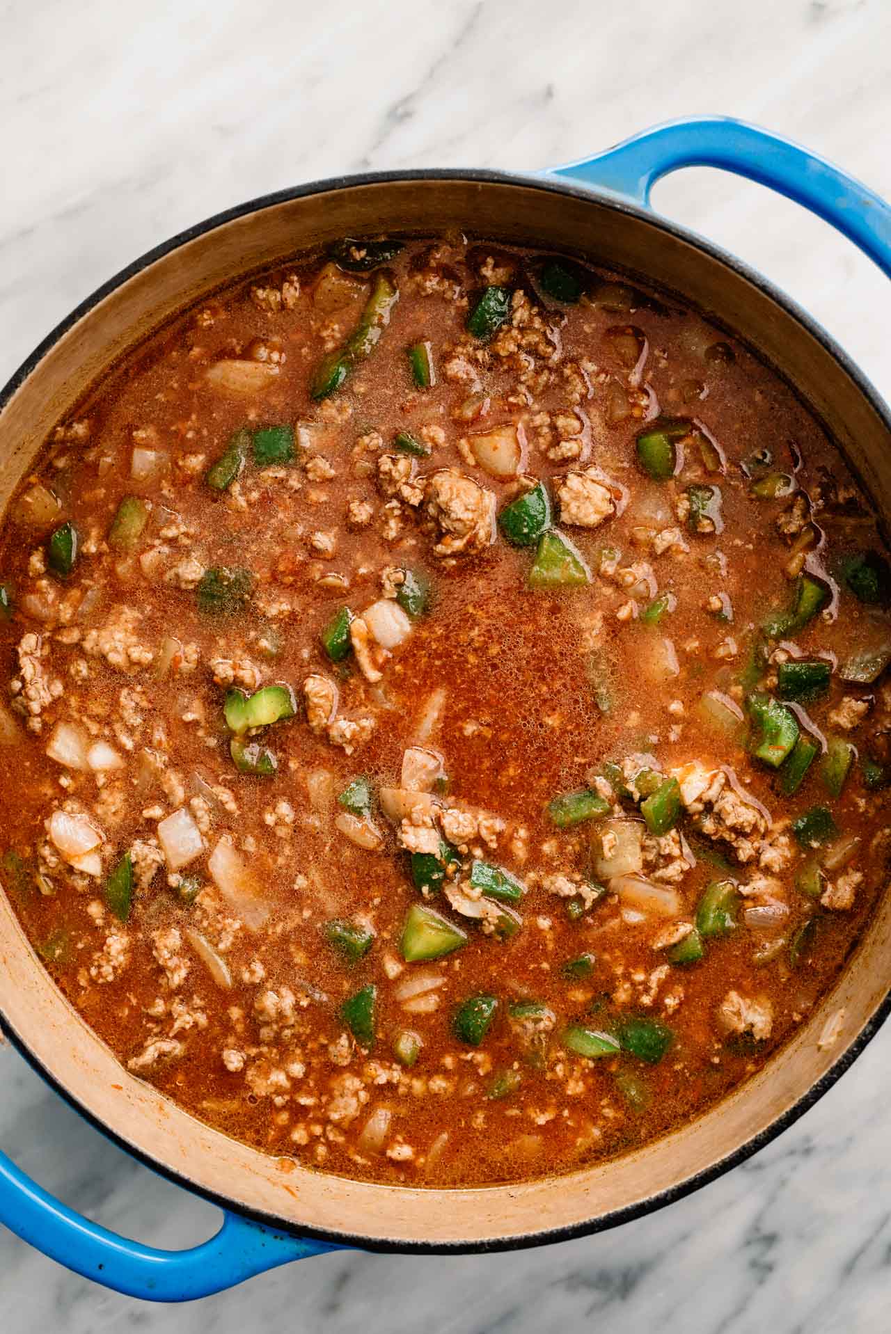 Add broth, tomatoes and seasoning to ground beef in a large pot.