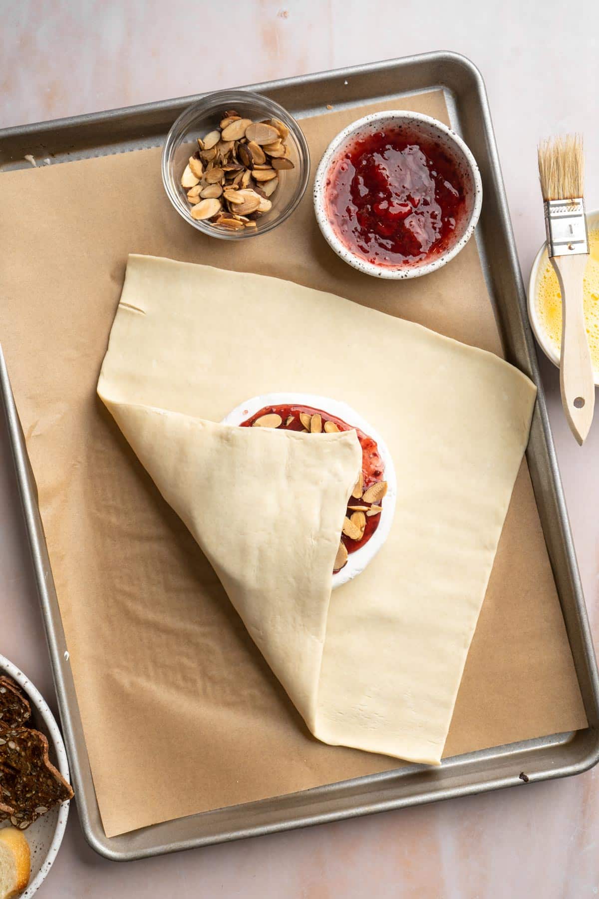 Folding puff pastry over a brie cheese wheel.