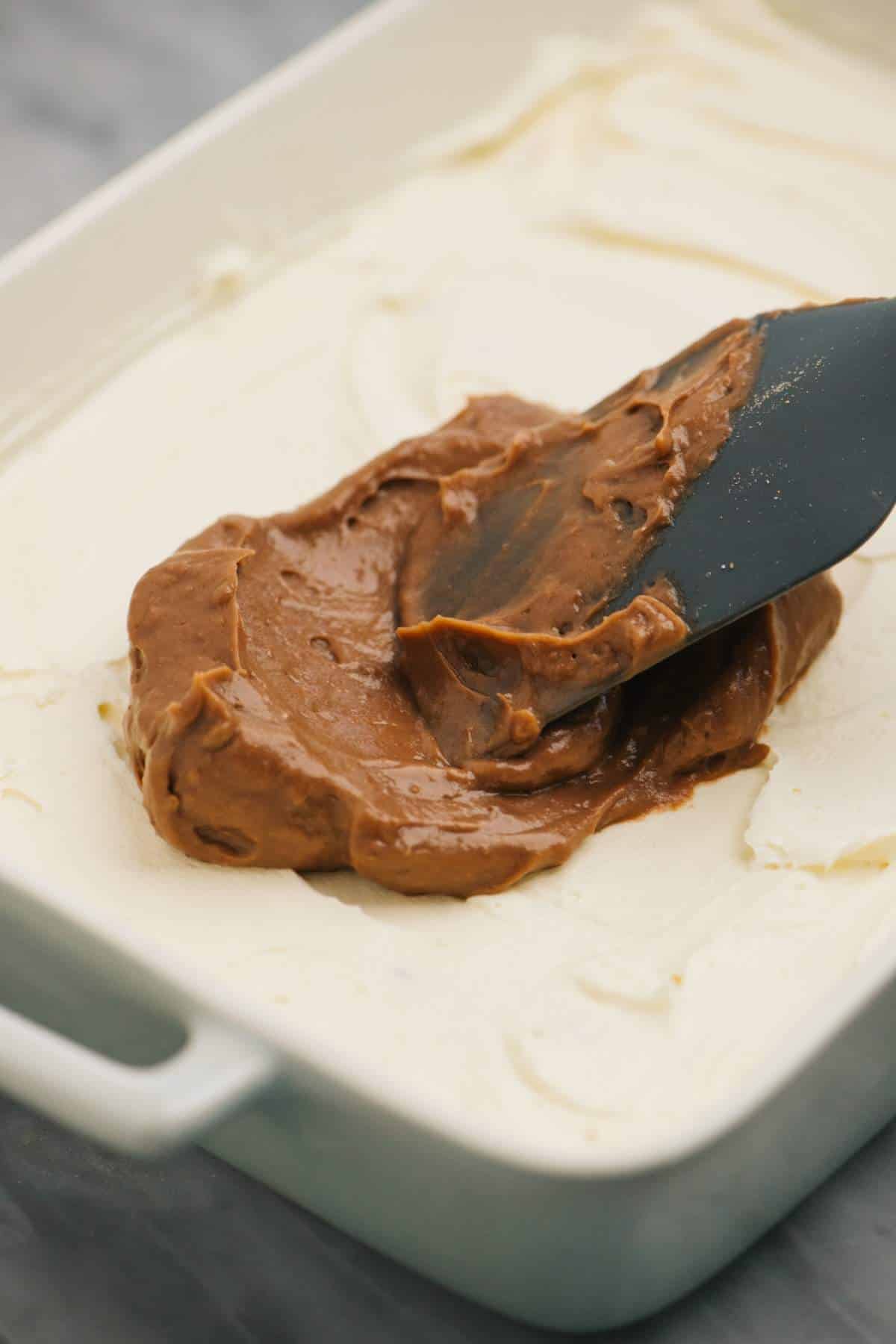 Spreading chocolate pudding over cream cheese mixture.