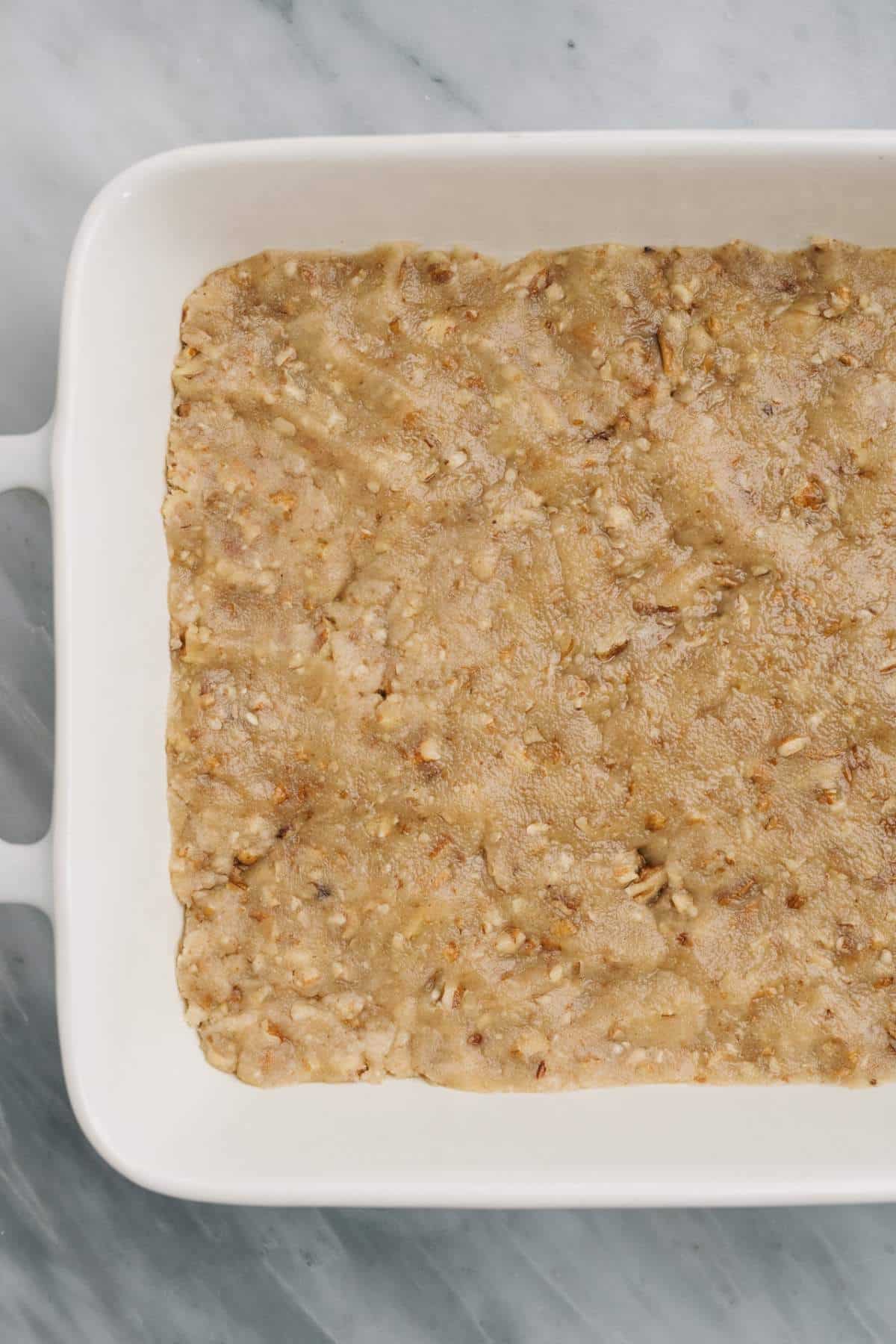 Cookie crust pressed into a white baking dish.