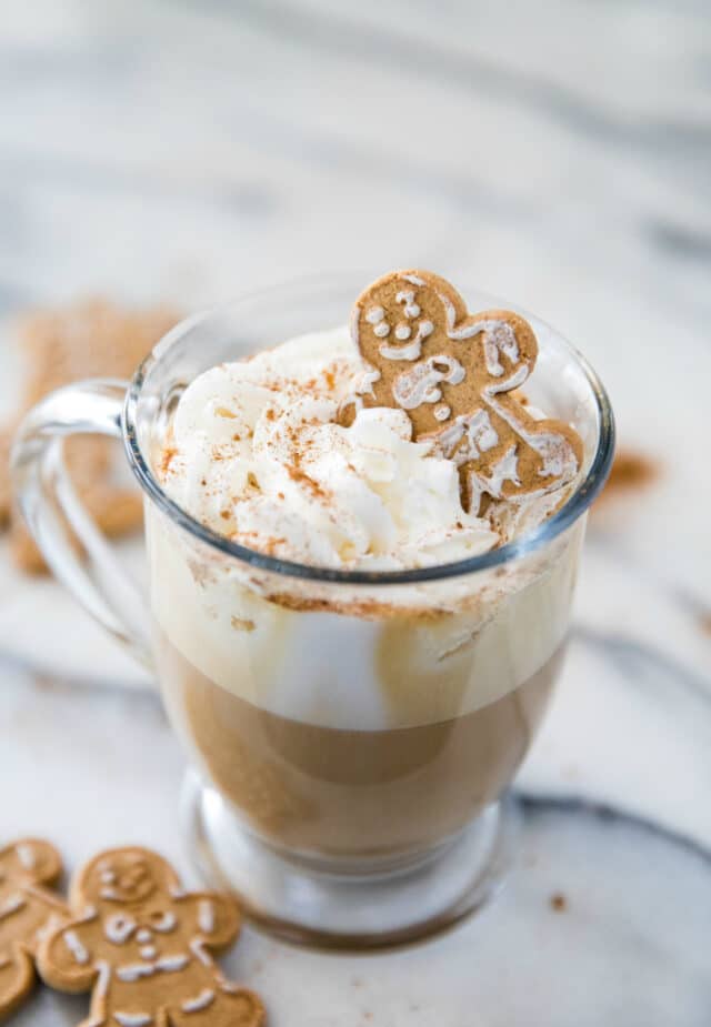 coffee in a glass mug with whipped cream and a gingerbread cookie