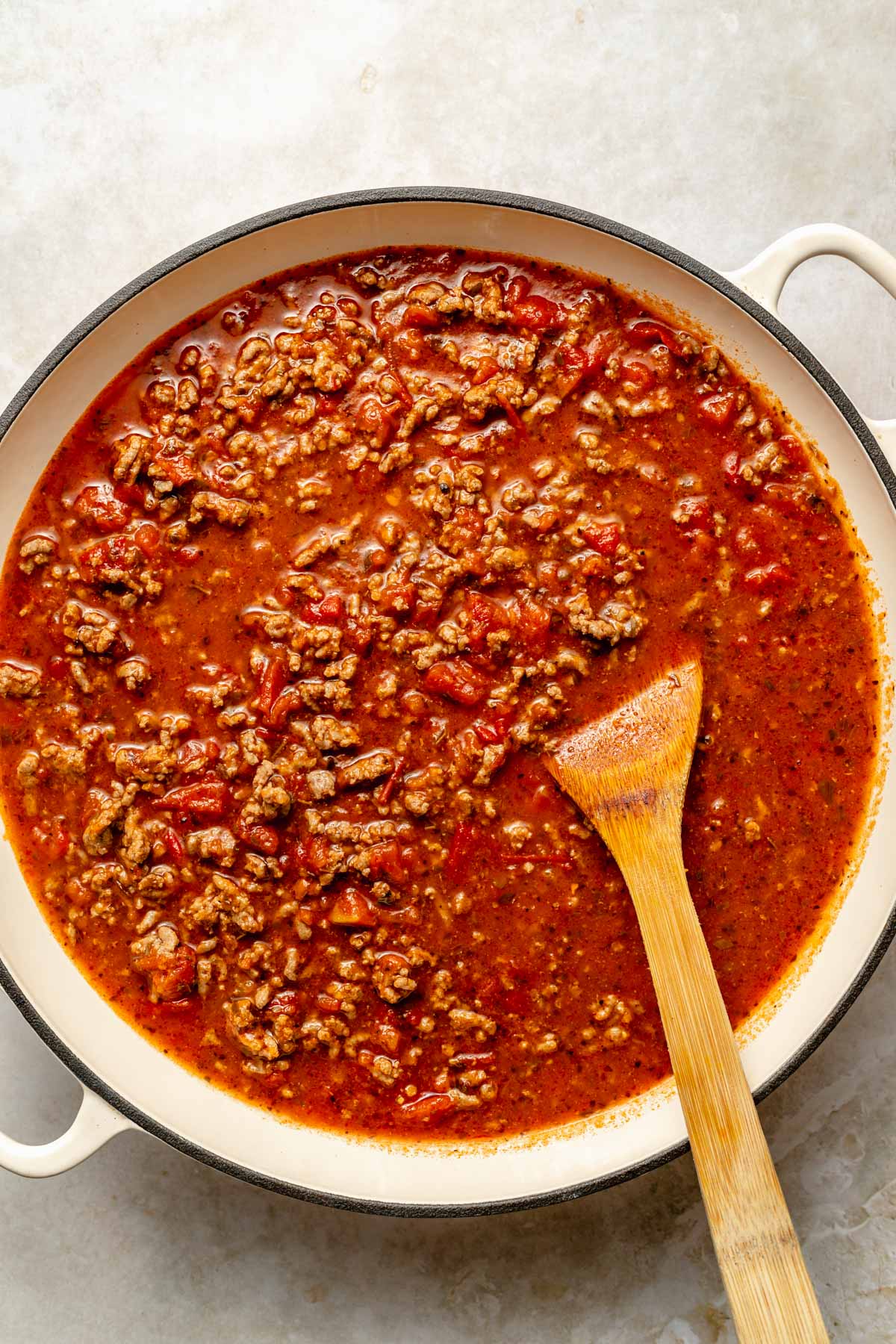 Stirring meat sauce in a large pot.