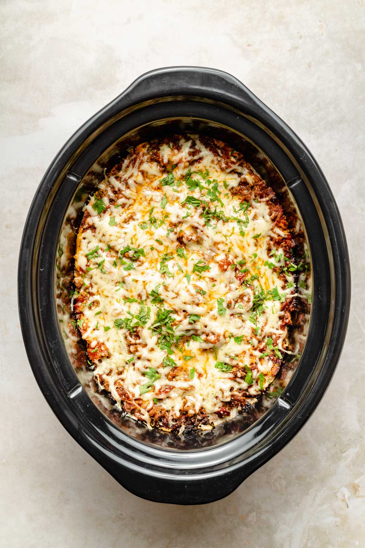 Cooked crockpot lasagna topped with fresh parsley.