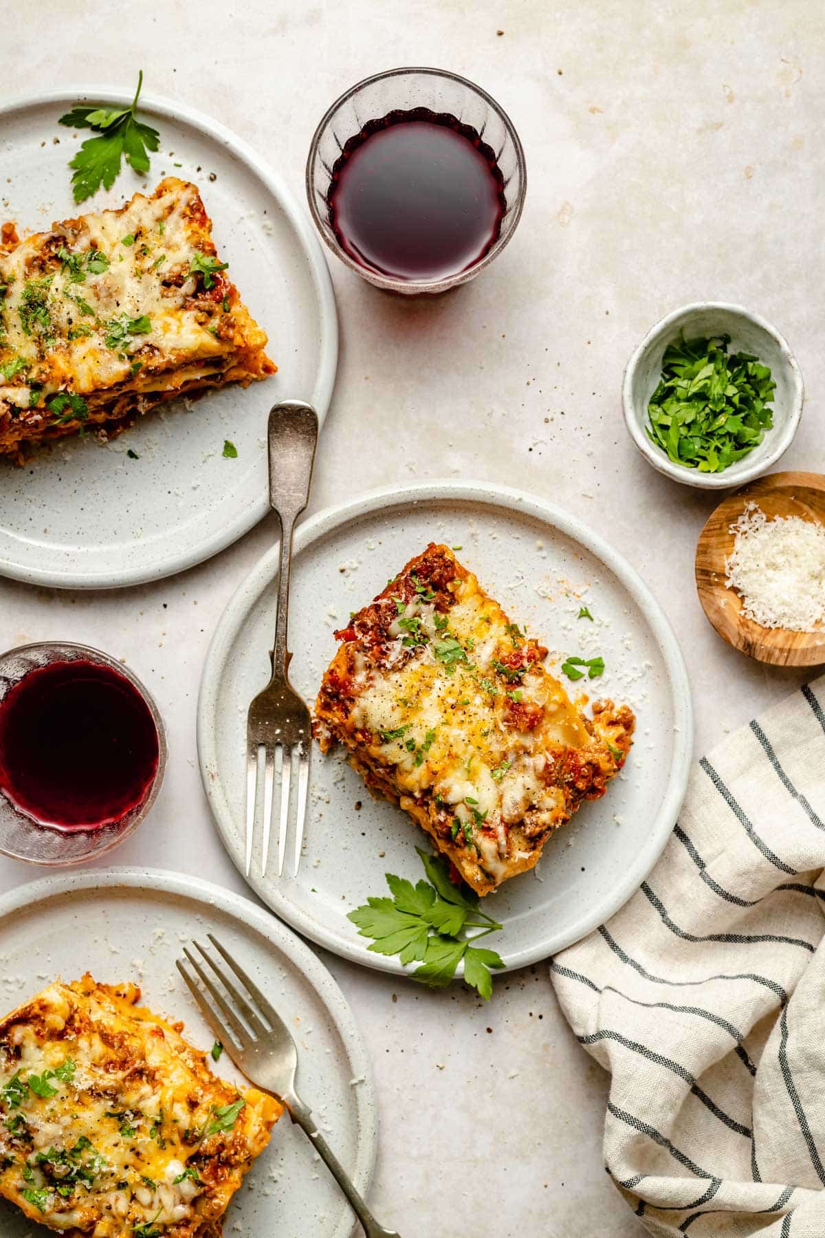 servings of crockpot lasagna on plates served with wine