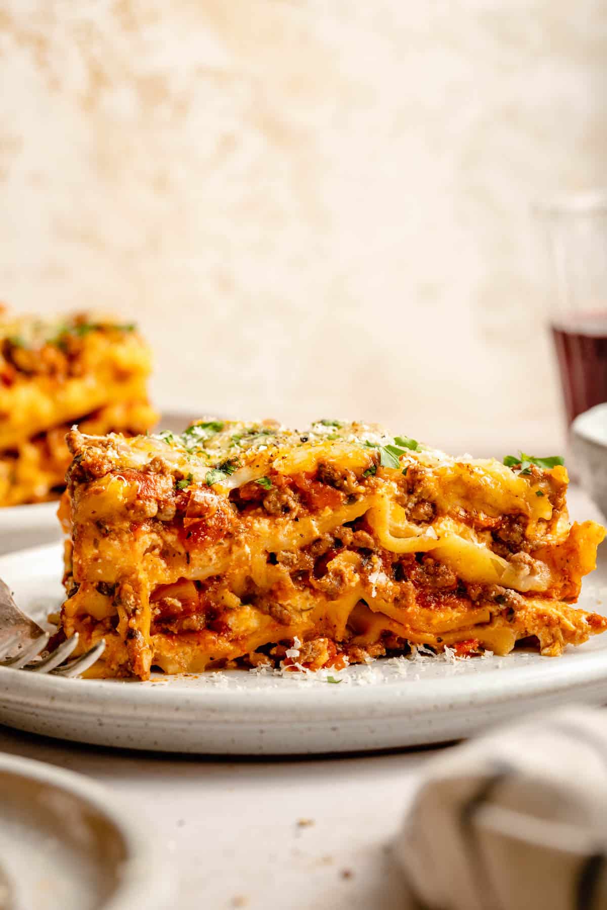 slice of lasagna on a white plate garnished with fresh parsley