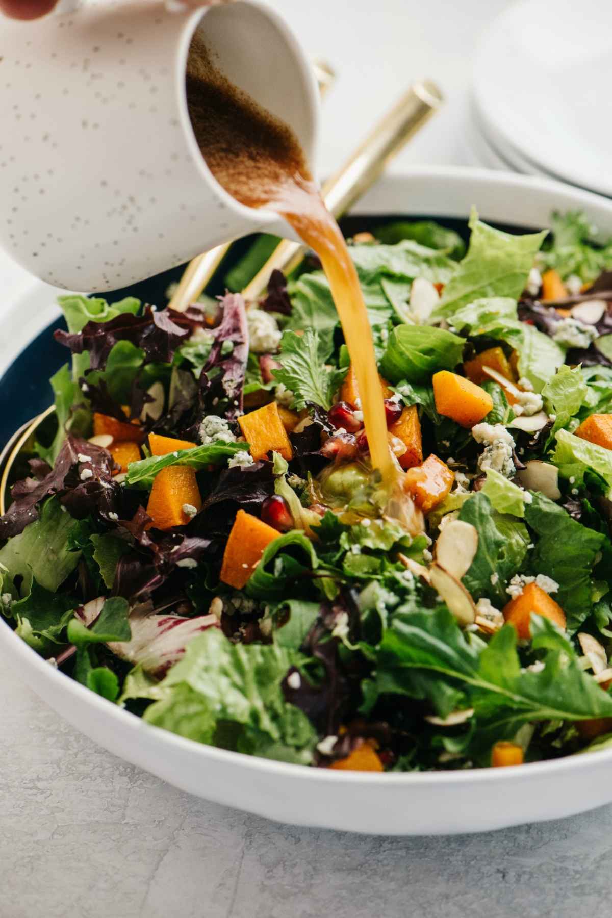 Pouring a vinaigrette onto a butternut squash salad.