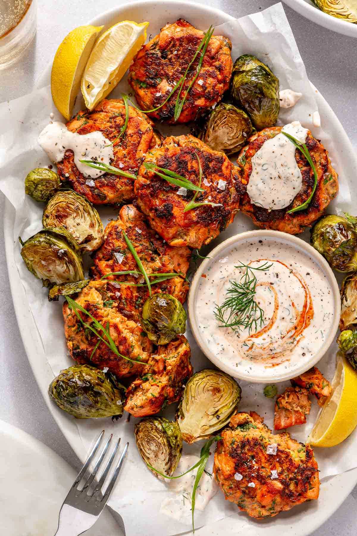 Sweet potato salmon cakes served with Brussels sprouts and a creamy sriracha sauce.