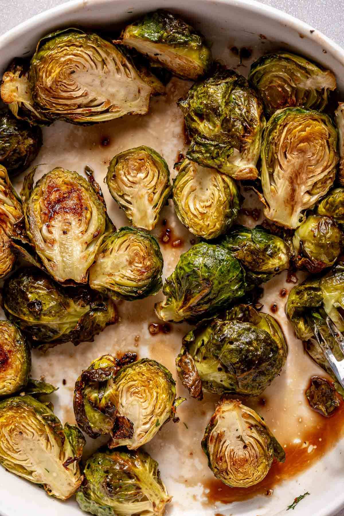 Tossing brussels sprouts with maple syrup and balsamic vinegar.