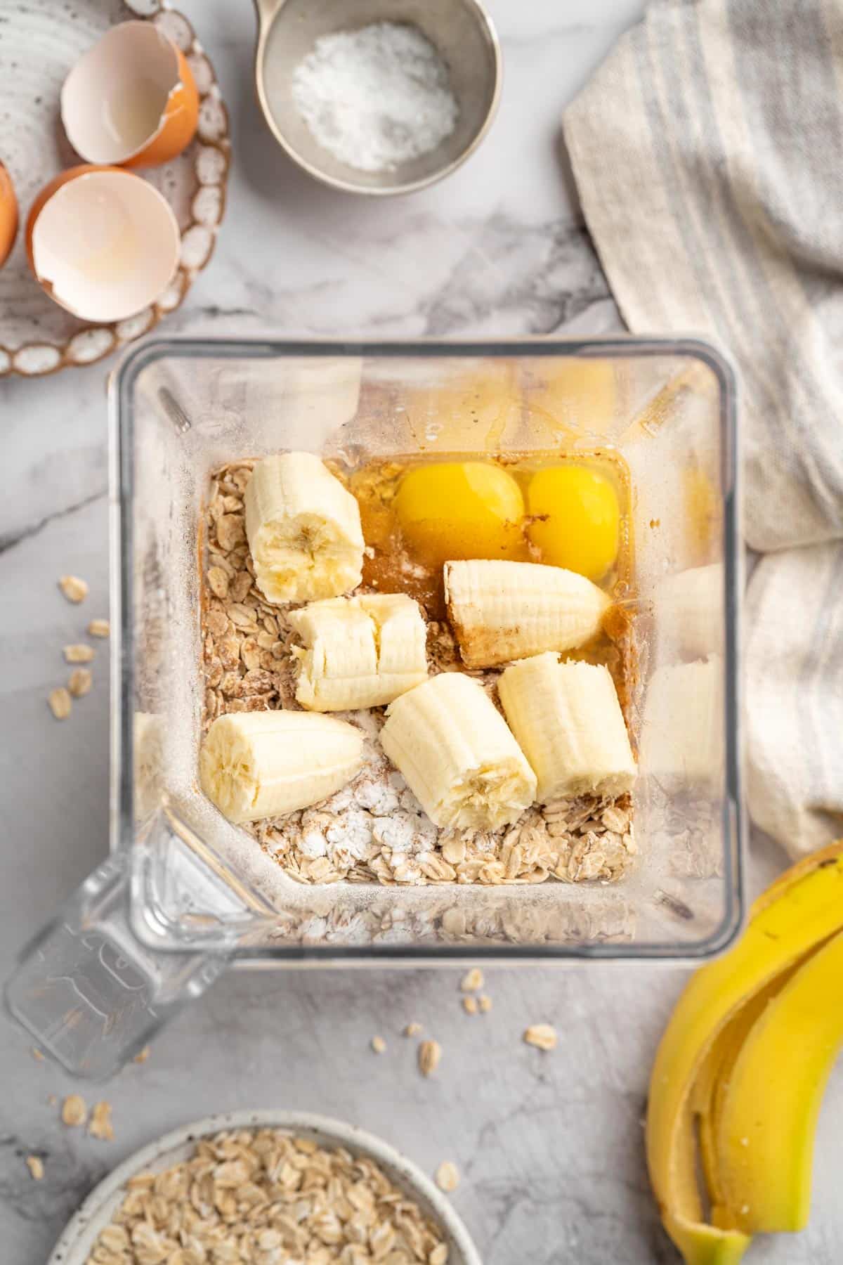 Chunks of banana, eggs, oats, maple syrup and baking powder in a blender.