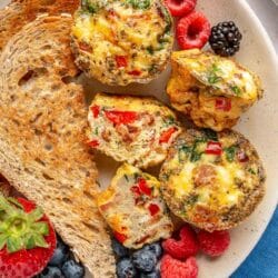 Egg muffin cups on a plate with toast and berries.