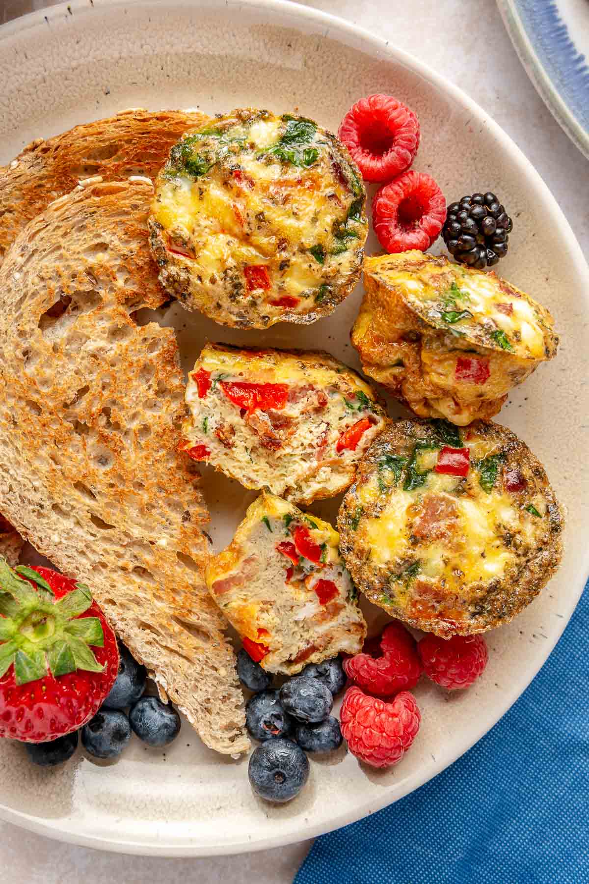 Egg muffin cups on a plate with toast and berries.