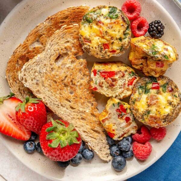 Egg muffin cups on a plate with toast and berries.