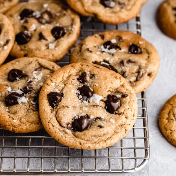 Chewy chocolate chip cookies stacked on a wire cooling rack.