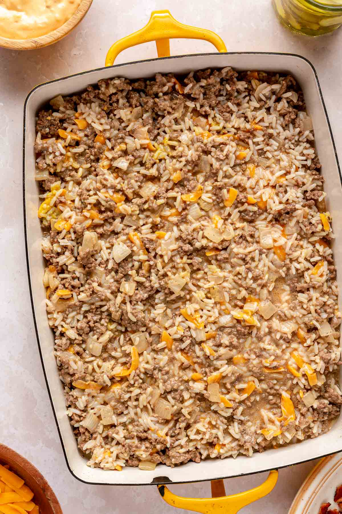 Mixture of shredded cheese, greek yogurt, ground beef and rice in a casserole dish.