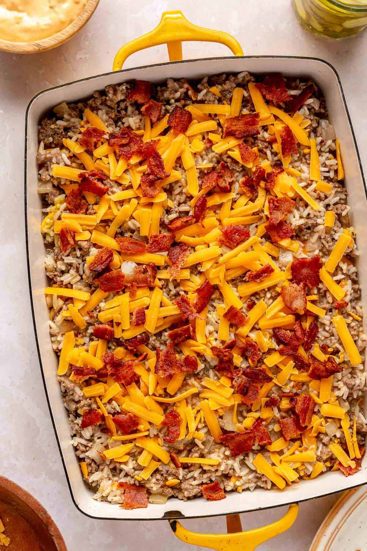 Casserole topped with shredded cheddar cheese and bacon.