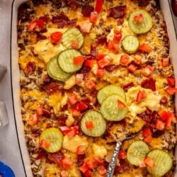 Cheeseburger casserole topped with pickle slices, diced tomatoes and bacon.