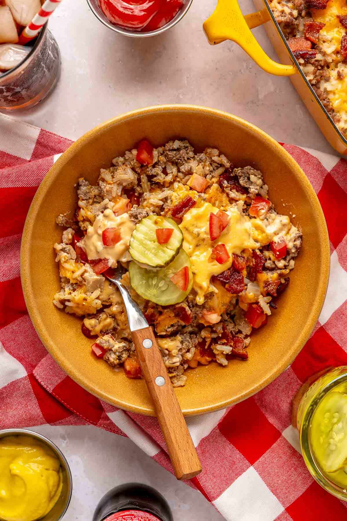 Cheeseburger casserole served in a bowl with pickle slices and burger sauce.