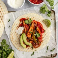 Chicken fajitas topped with salsa, sour cream and sliced avocado.