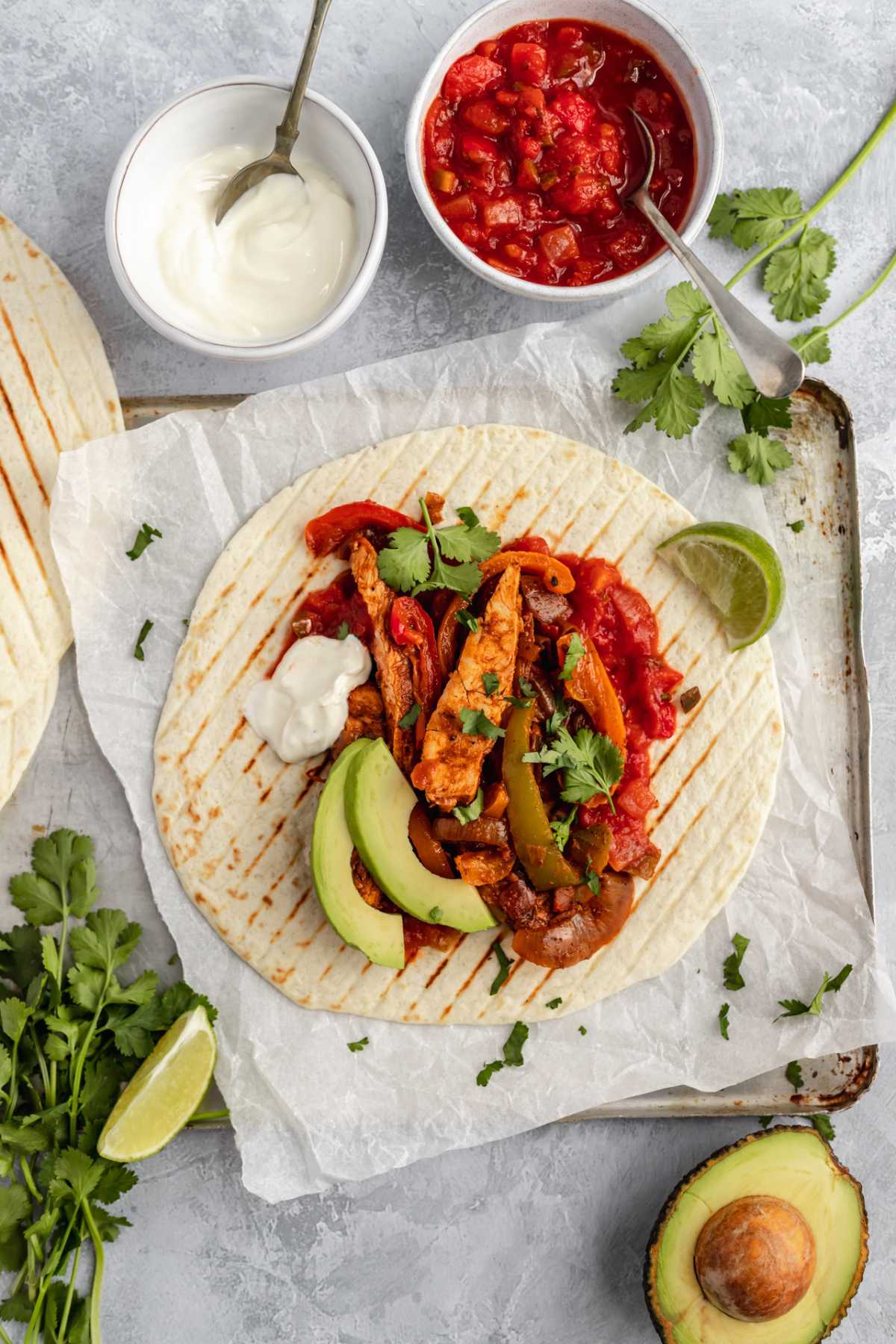 Chicken fajitas topped with salsa, sour cream and sliced avocado.