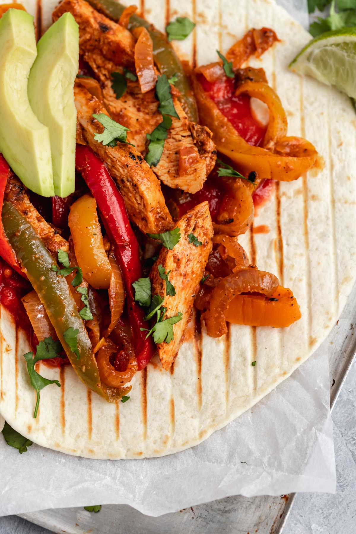 Chicken fajitas in a tortilla with avocado.