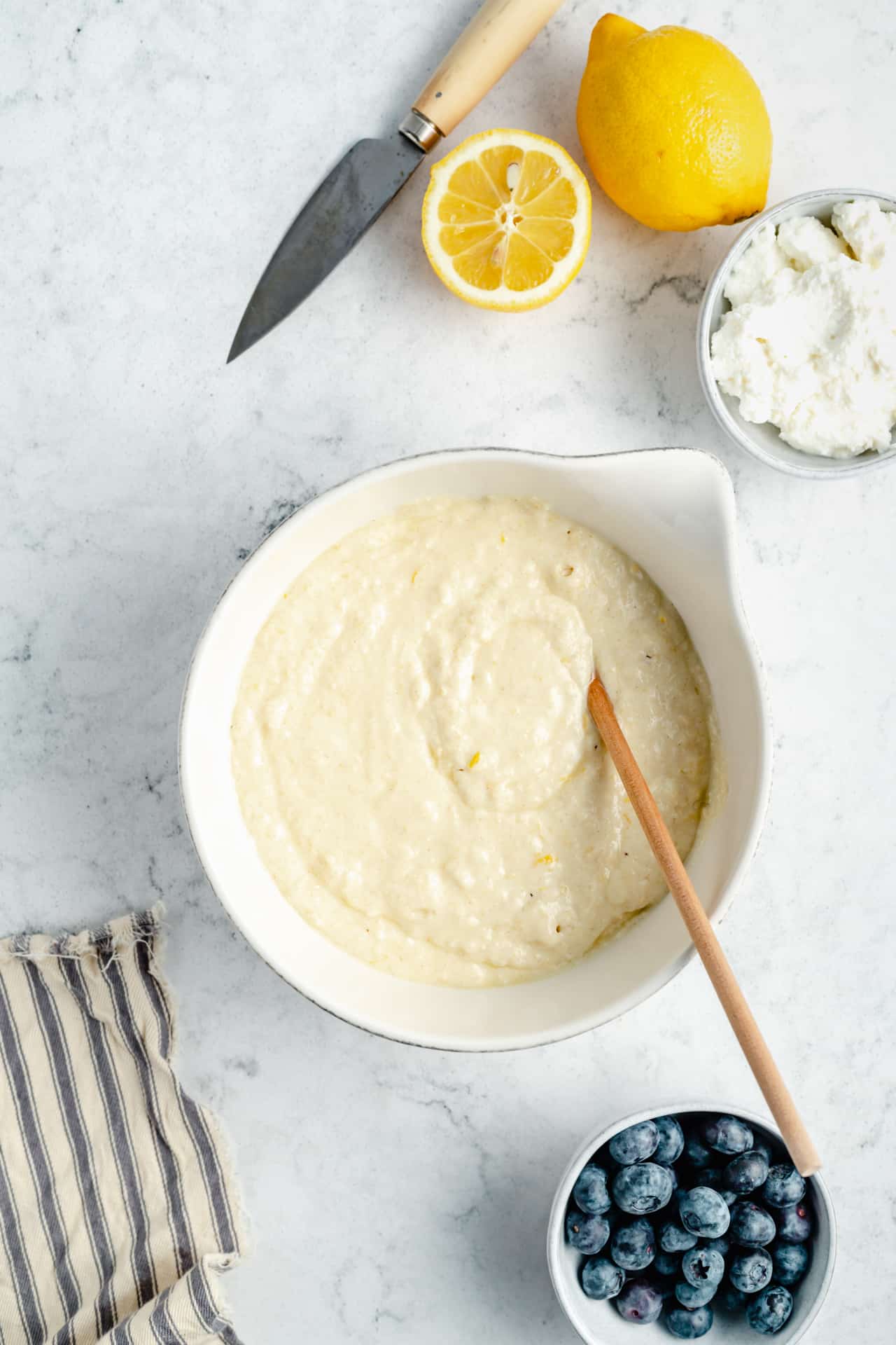 stirring batter for lemon ricotta pancakes in a large mixing bowl