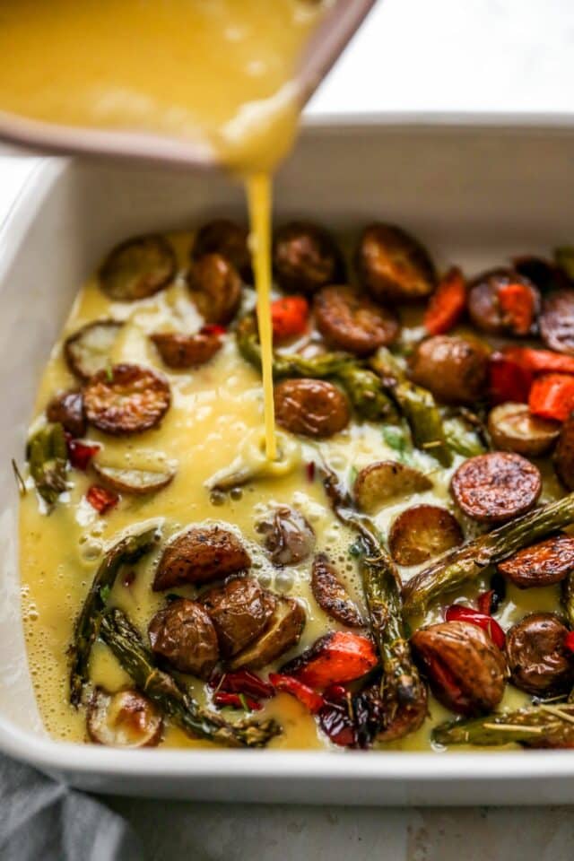 Pouring eggs over roasted vegetables.