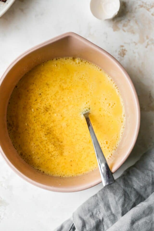 Beating eggs in a large bowl.