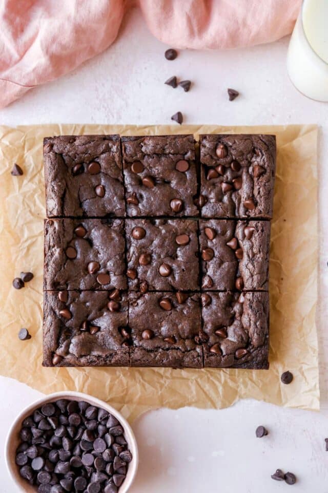 Brownies sliced into small squares on parchment paper.