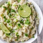 Cilantro lime rice topped with cilantro and lime wedges.