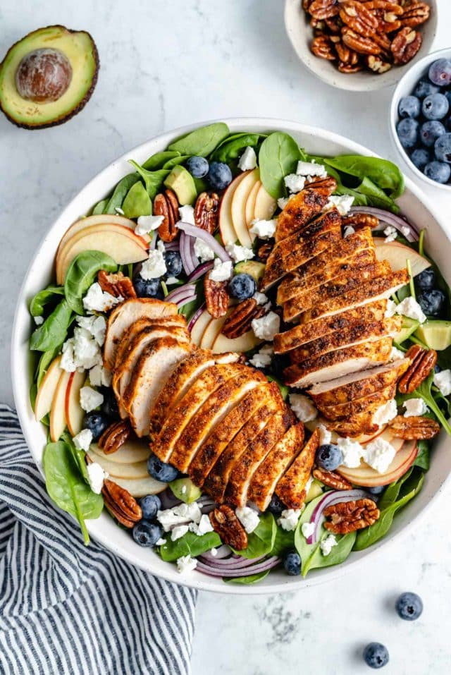 spinach salad with chicken in a large white serving bowl