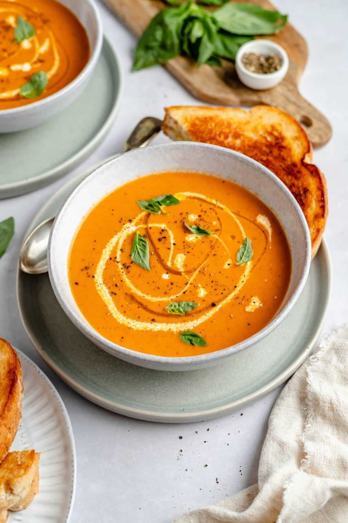 roasted tomato soup in a bowl and a grilled cheese near the bowl