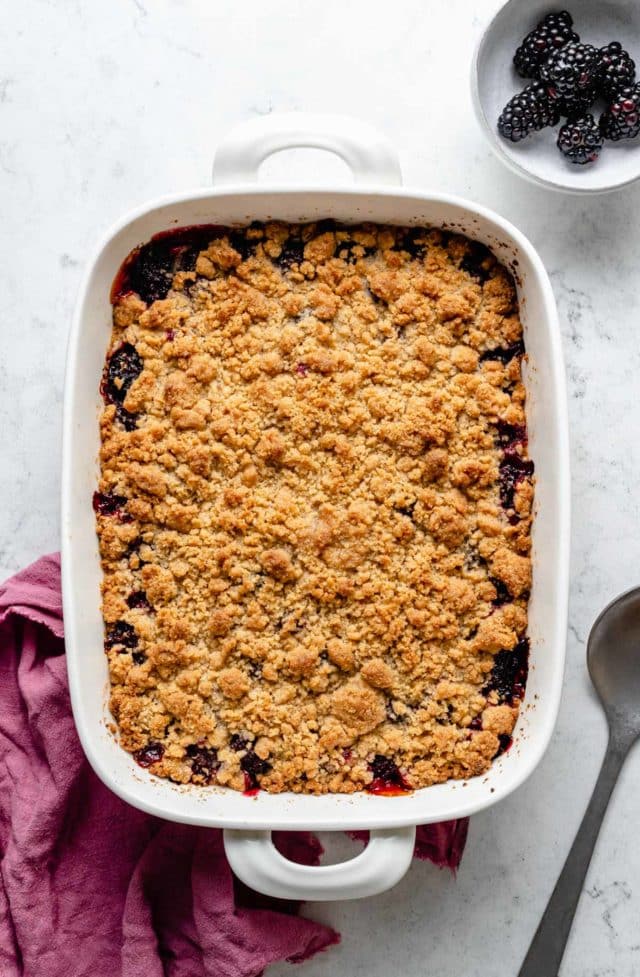 Baked blackberry crumble in a white baking dish.