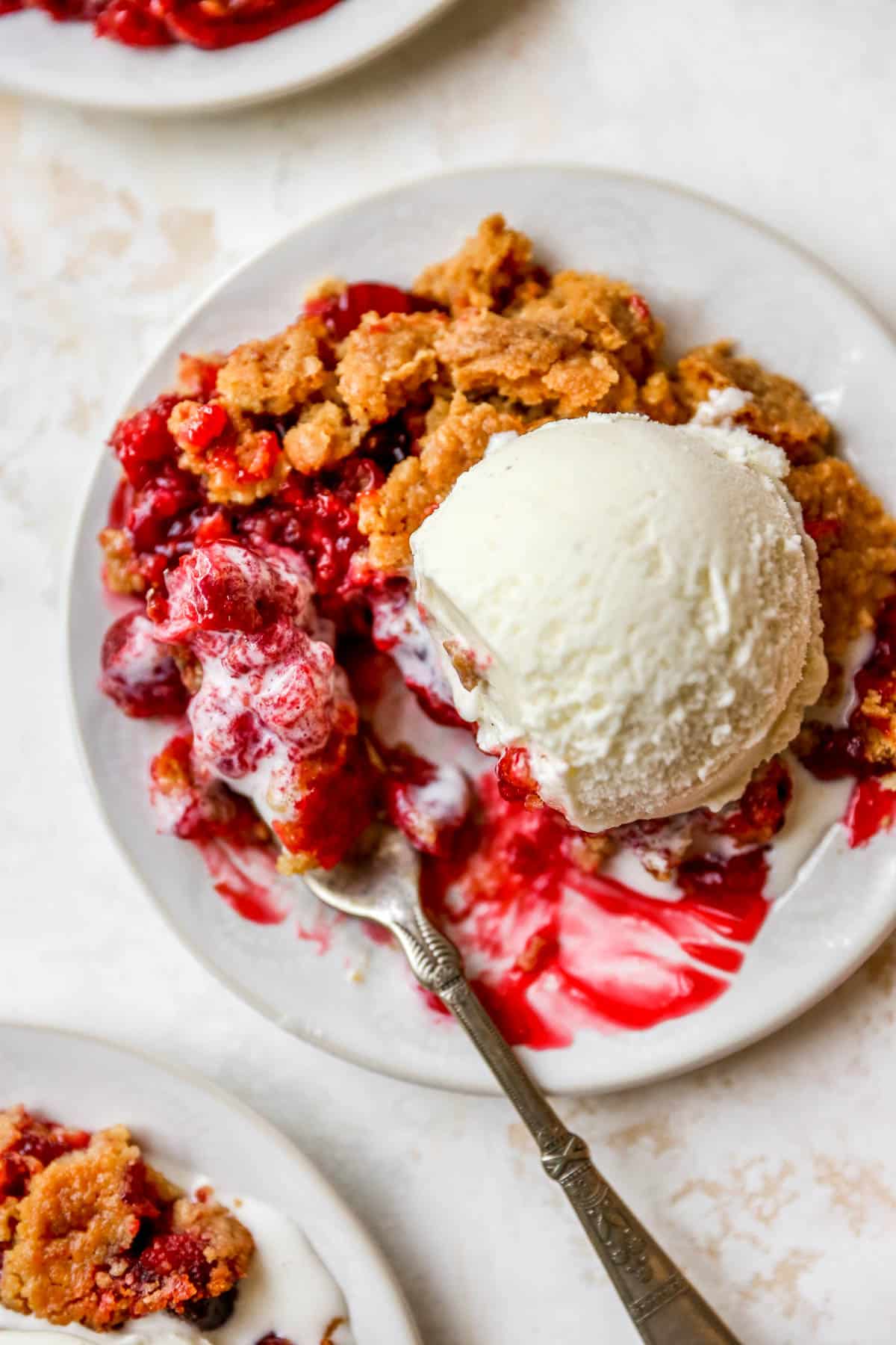 Taking a fork of cherry dump cake with vanilla ice cream.