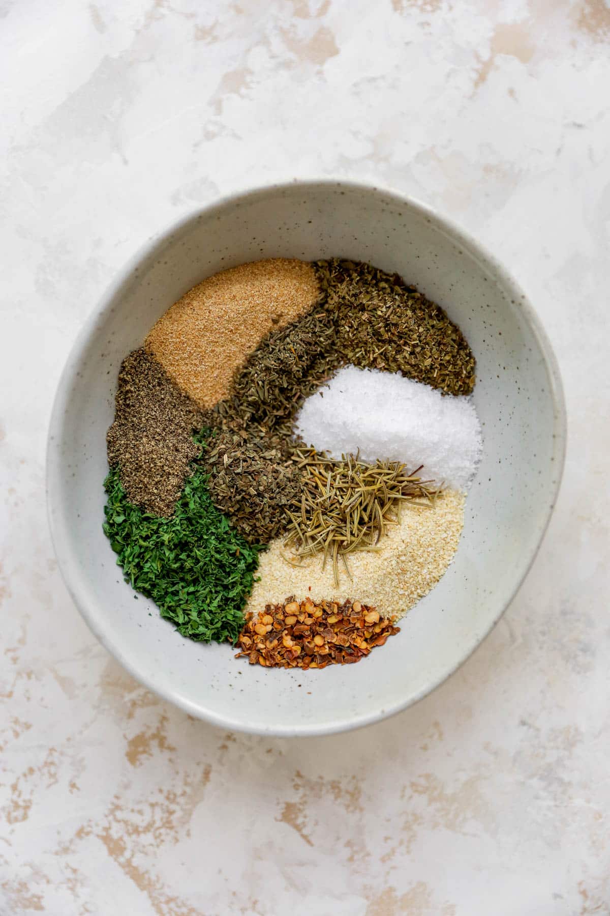 Mixing a variety of spices together in a small white bowl.