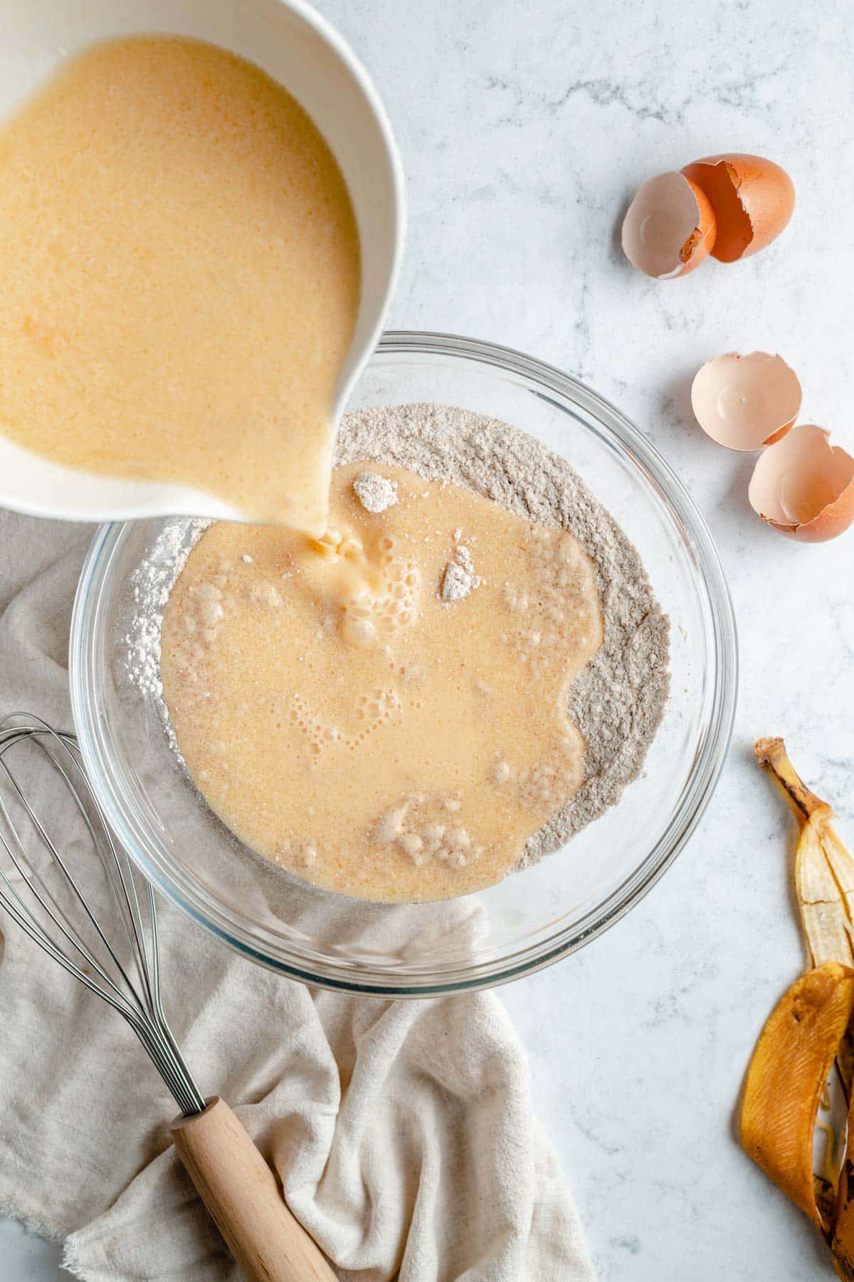 Adding wet ingredients to dry ingredients in a large mixing bowl.