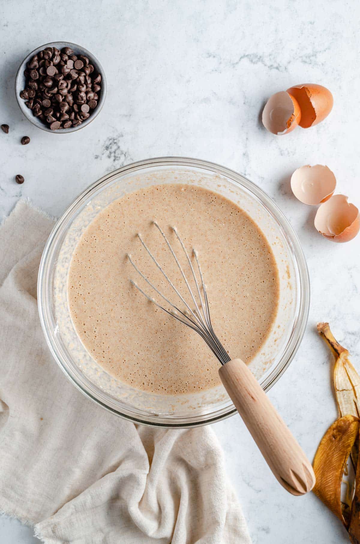 Mixing wet ingredients for waffles in a large mixing bowl with a whisk.