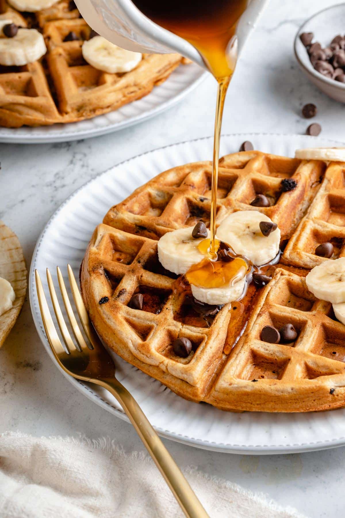 Drizzling syrup over the top of chocolate chip waffles.