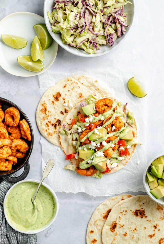 shrimp tacos served with avocado sauce and lime wedges