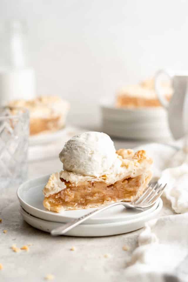 slice of apple pie topped with a scoop of ice cream, served on a white plate 