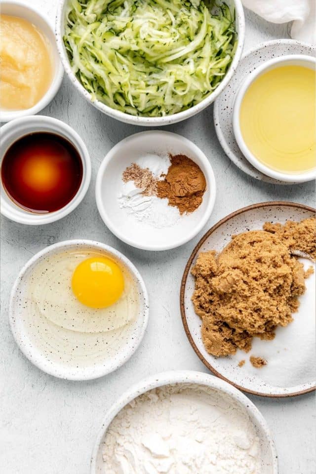 ingredients for making zucchini bread in small white bowls