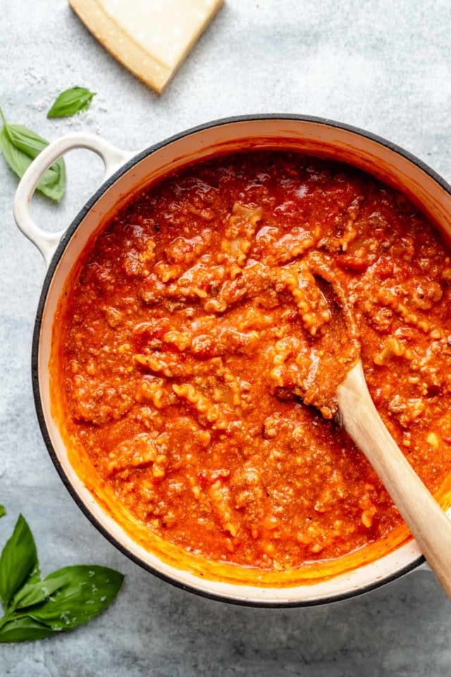 stirring noodles into a large pot of lasagna soup