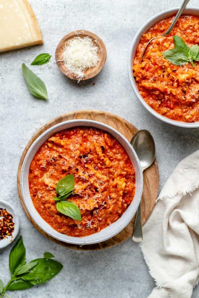 bowls of lasagna soup served with fresh basil and parmesan cheese