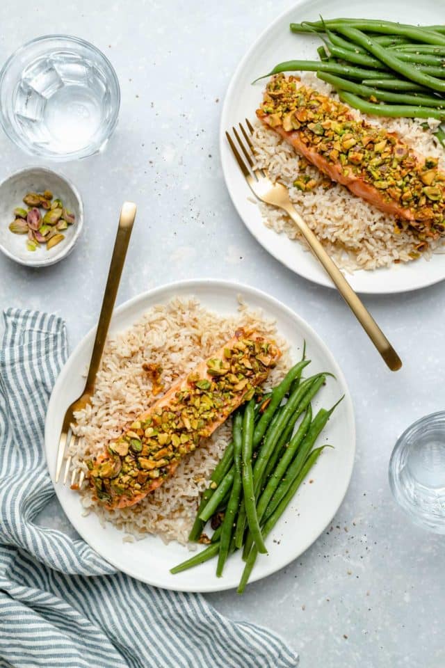 two plates with rice, green beans and pistachio-crusted salmon