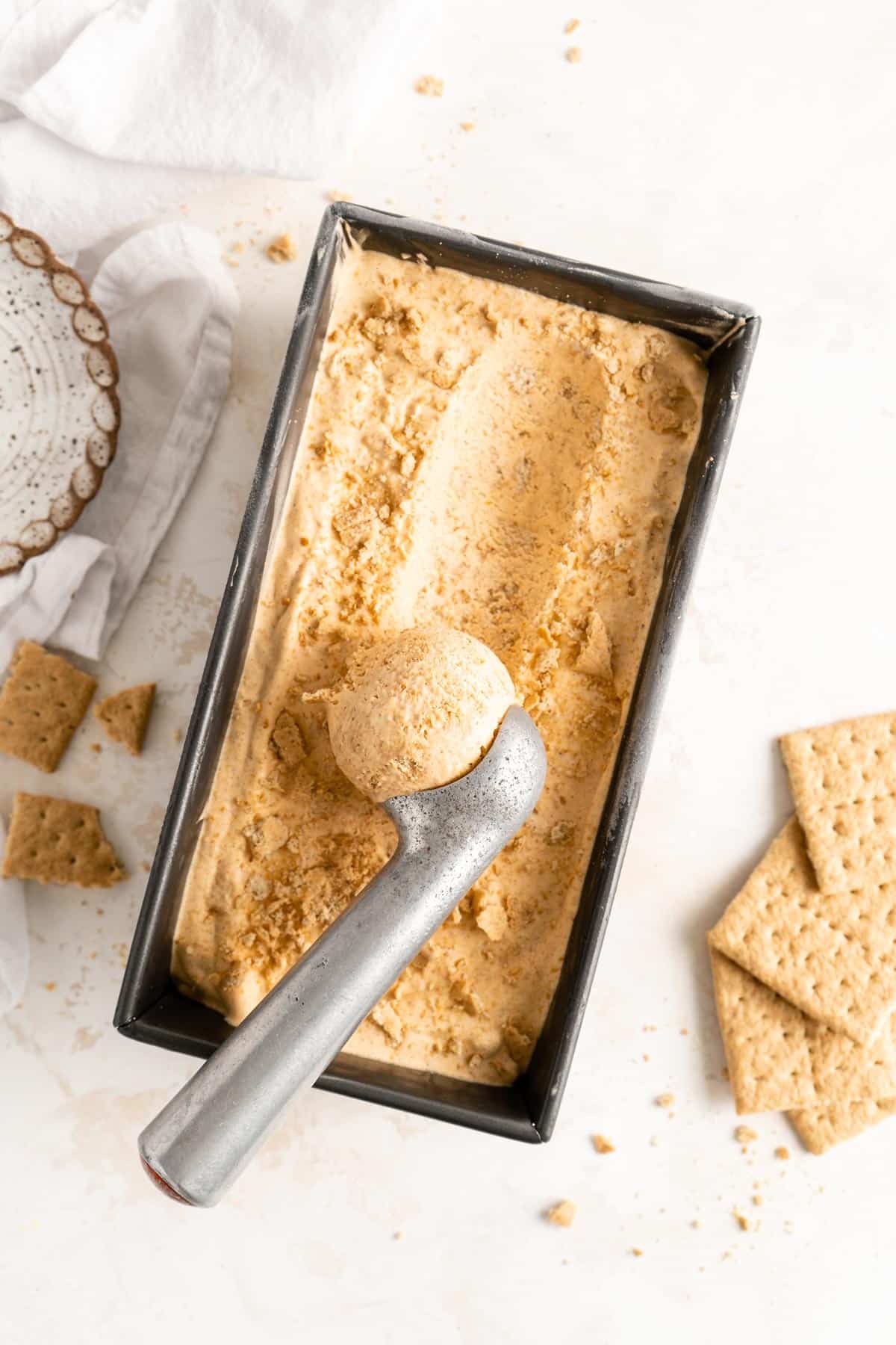 using an ice cream scoop to scoop out a serving of pumpkin ice cream