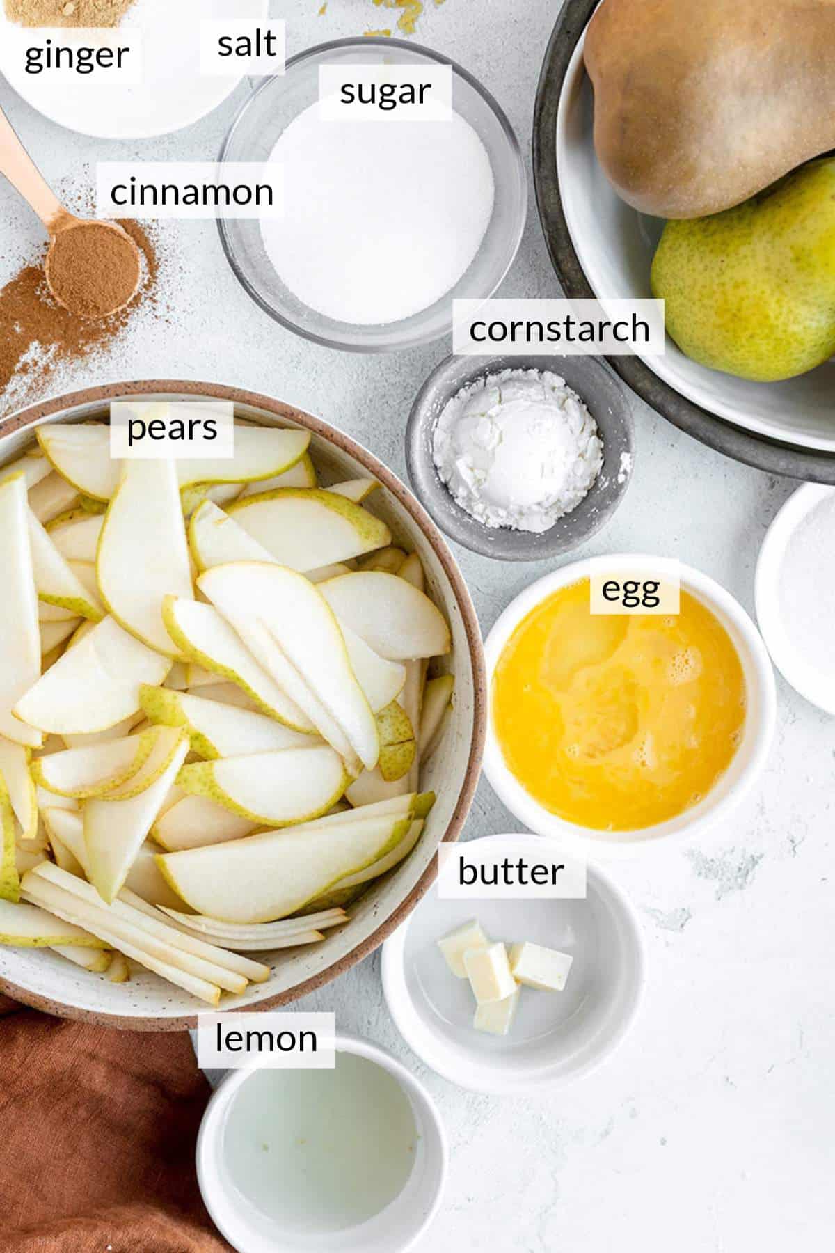 Bowl filled with sliced pears, sugar, egg, butter, spices and lemon juice.