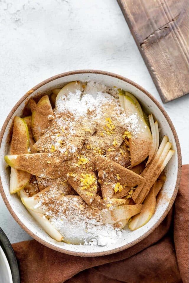 Tossing pear slices in flour, cinnamon and sugar.