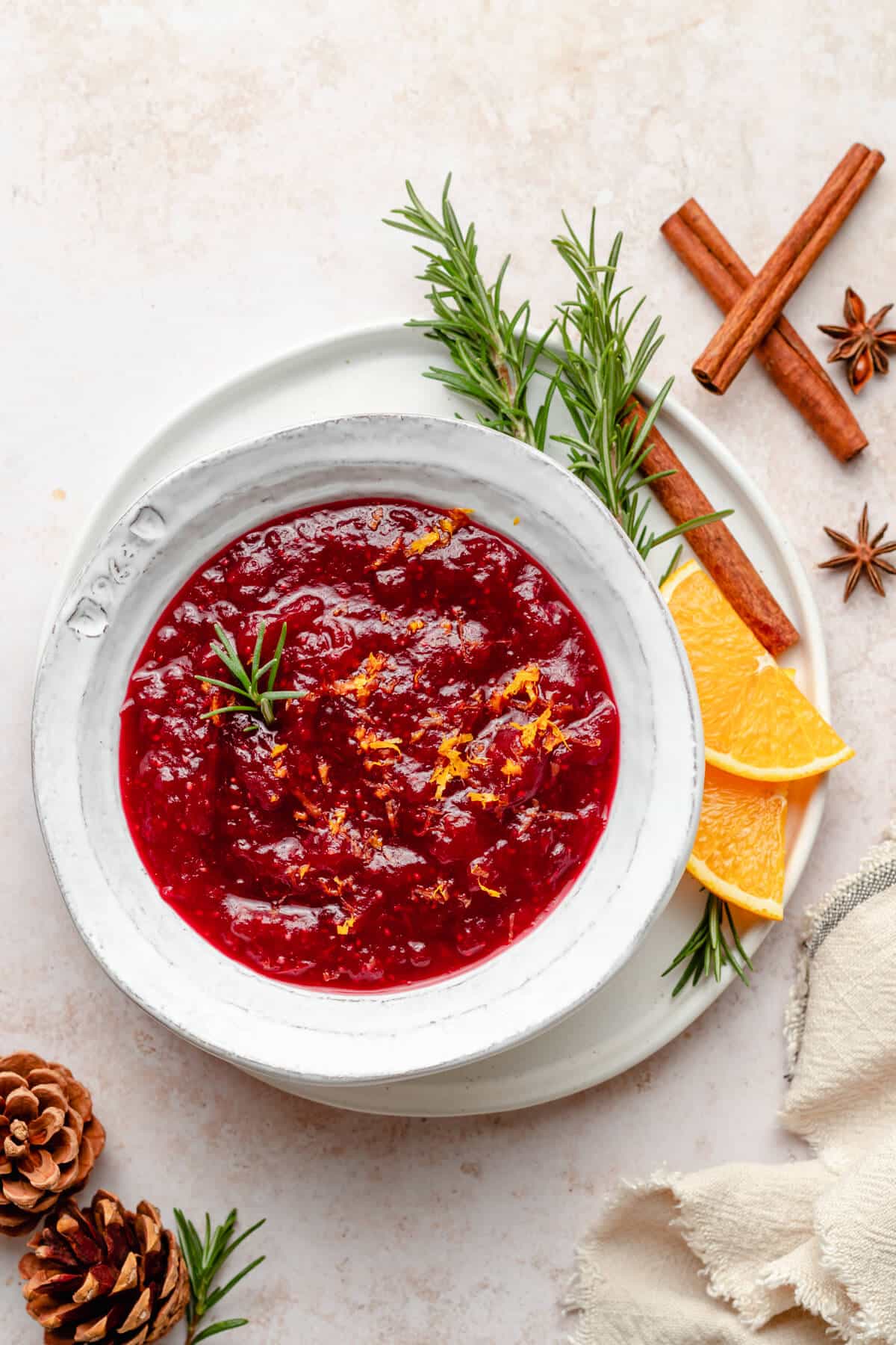 Healthy cranberry sauce in a bowl with fresh rosemary and orange slices.