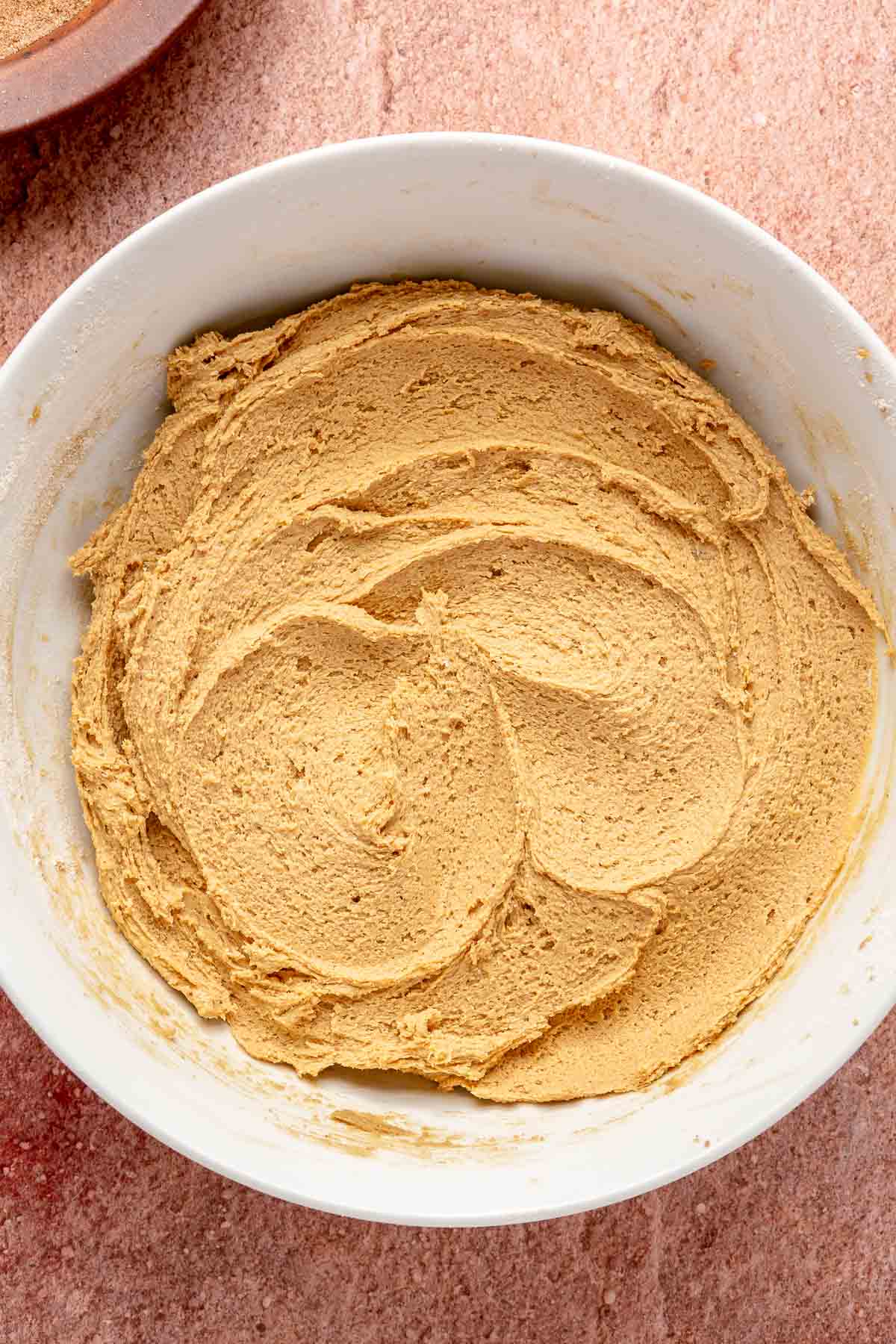 Flour combined with wet ingredients to form a cookie dough in a bowl.