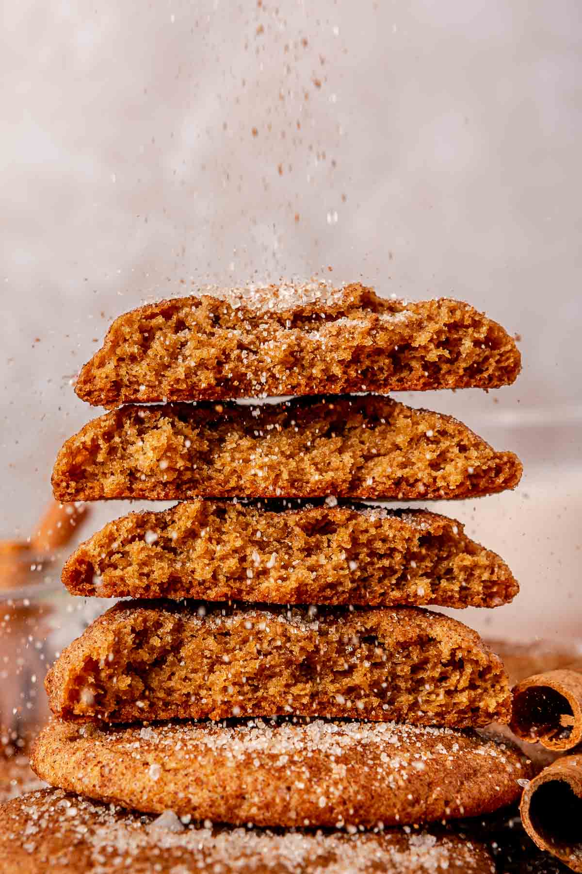 Sprinkling cinnamon and sugar over a stack of broken cookies.