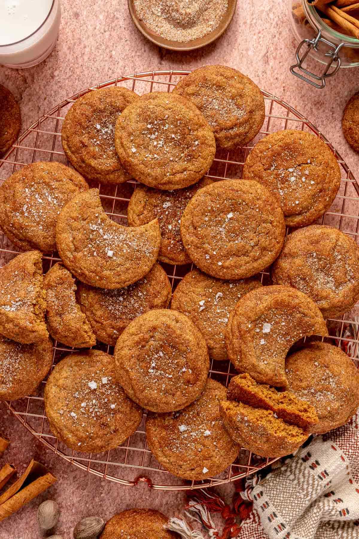 Cinnamon cookies on a wire rack near a glass of milk.